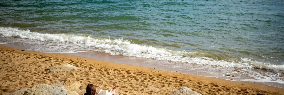 Eine Frau liest am Strand